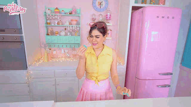 a woman standing in front of a pink refrigerator that says precioso on it