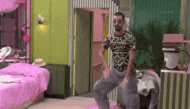 a man in a dolce & gabbana shirt is dancing in a pink room