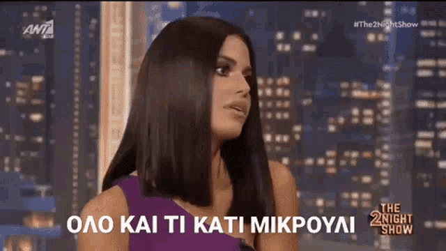 a woman in a purple dress is talking on the night show in greek .
