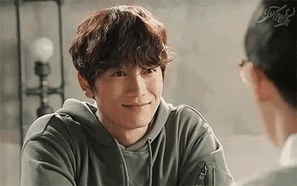a man in a green hoodie is smiling at another man .