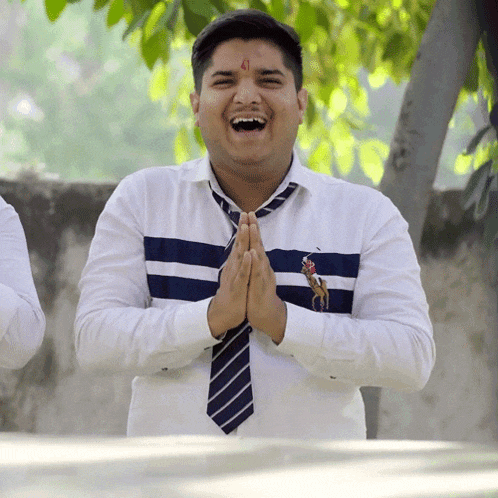a man wearing a polo shirt and tie is laughing with his hands folded