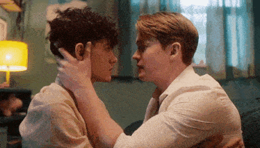 two men are touching each other 's foreheads in a bedroom .