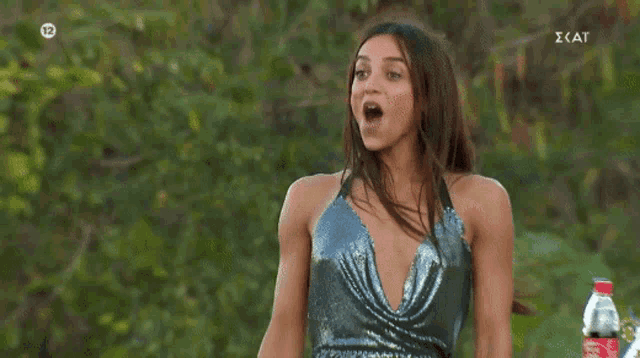 a woman in a silver sequined dress is smiling and holding her arm in the air