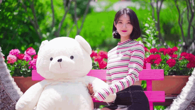 a woman is sitting on a pink bench holding a large teddy bear