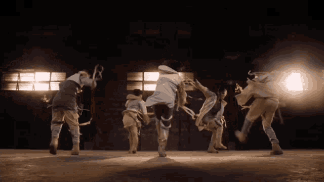 a group of people are dancing in a dark room with lights shining on them