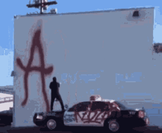 a police car is parked in front of a white building with graffiti on it