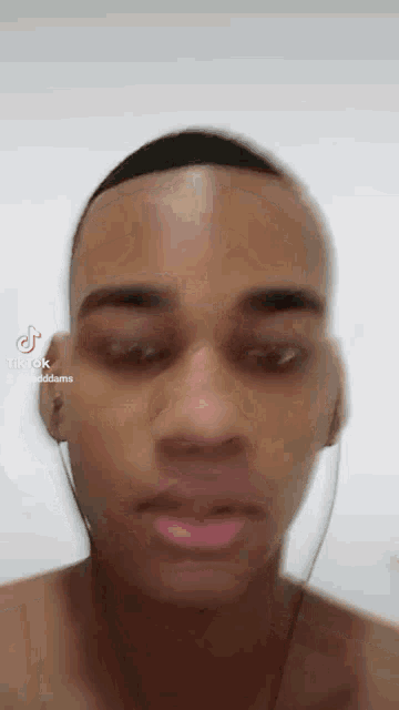 a man without a shirt is wearing headphones and looking at the camera with tiktok written on the bottom