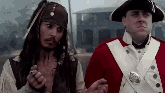 a man dressed as a pirate is standing next to a man dressed as a soldier .