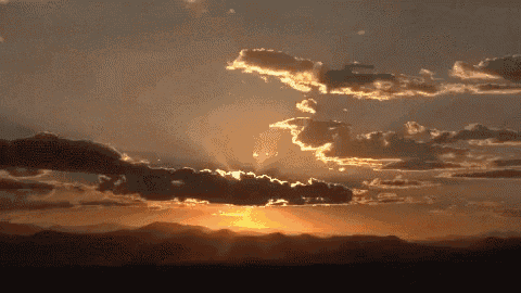 the sun shines through the clouds at sunset over the mountains