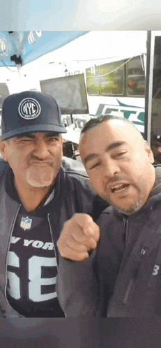 two men are posing for a picture and one is wearing a nyc jersey