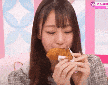 a girl is eating a fried chicken wing in front of a pink sign that says " どんな 時 "