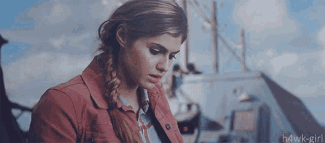 a woman with a braided ponytail is wearing a red jacket and a blue shirt