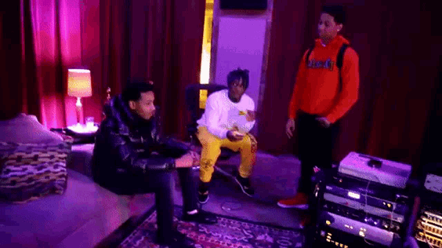 a group of young men are sitting on a couch in a room with purple lights .