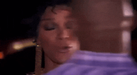 a woman in a purple shirt is kissing a man in a blue shirt .