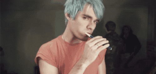 a young man with blue hair is brushing his teeth with a pen .
