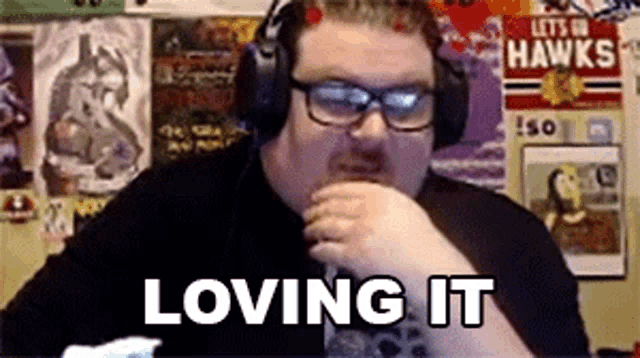 a man wearing headphones and glasses is saying loving it