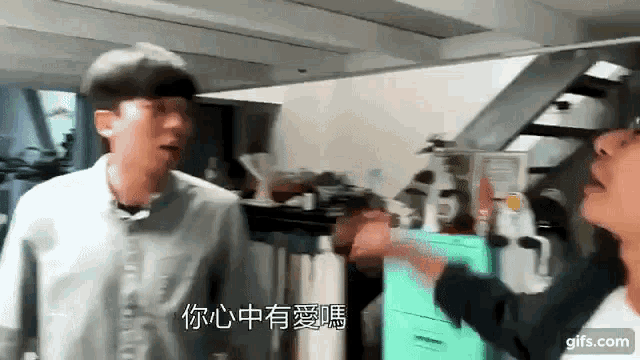 two men are standing next to each other in a room and one is pointing at the other .