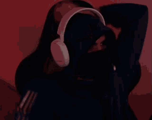 a man wearing headphones and a blue hoodie has his hands behind his head