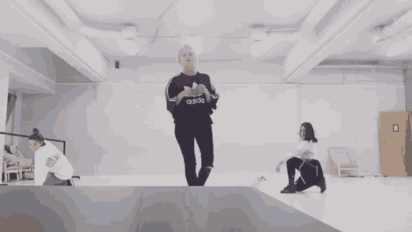 a woman wearing an adidas sweatshirt is jumping in the air