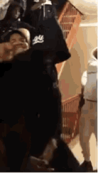 a group of people are standing in front of a staircase . one of the people is wearing a hoodie .