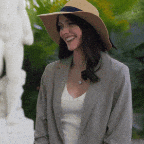 a woman wearing a hat and a jacket smiles for the camera