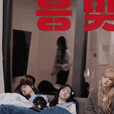 a group of girls are sleeping on a couch in front of a sign that says ' g5 '