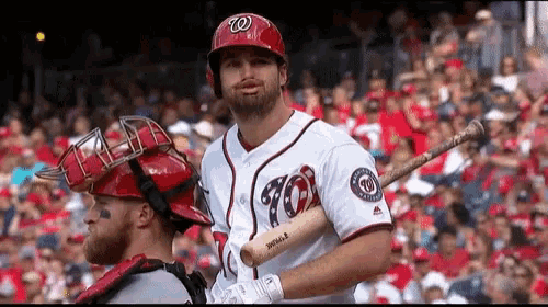 a baseball player wearing a washington nationals uniform holds a bat