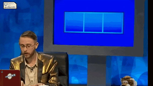 a man in a gold suit is sitting in front of a screen that says men