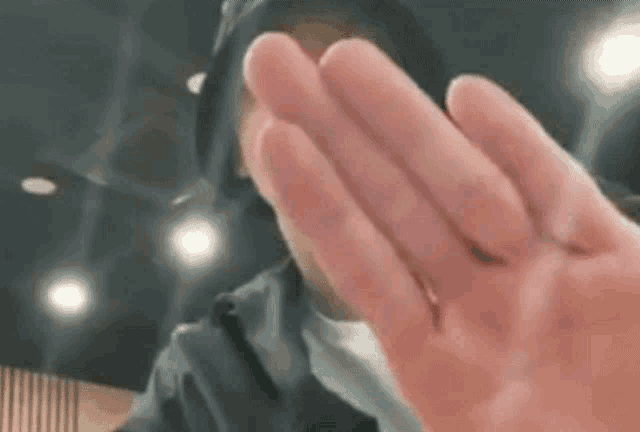 a close up of a person making a frame with their hand and smiling .