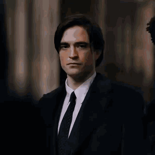 a man in a suit is standing in front of a crowd .
