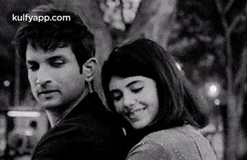 a man and a woman are hugging each other and smiling in a black and white photo .
