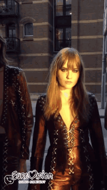 a woman in a leather outfit with eurovision going contest written on the bottom right