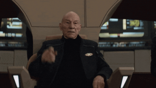 a bald man wearing a black jacket with a gold badge on his chest