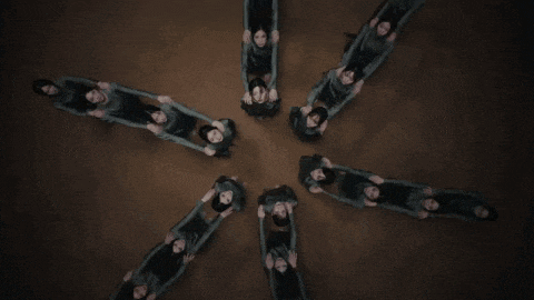 a group of people are laying in a circle with their heads down