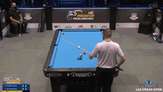 a man playing pool in front of a csi predator us pro billiard series sign
