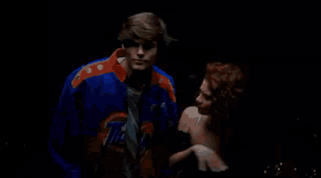 a man in a tide jacket is holding a woman 's arm