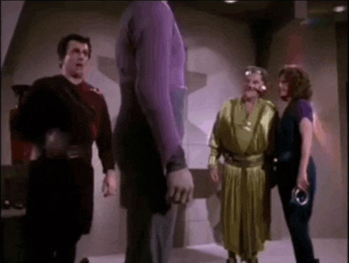a group of people are standing in a room talking to each other .