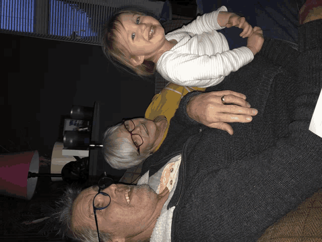a man and woman laying on a couch holding a child
