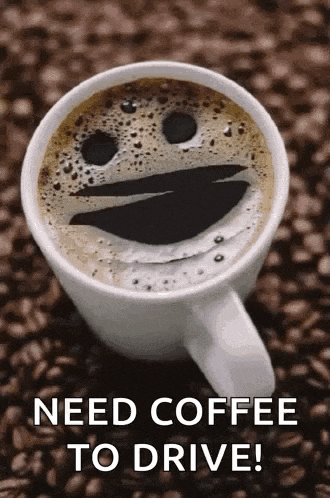 a cup of coffee with a smiley face on it is sitting on a pile of coffee beans .