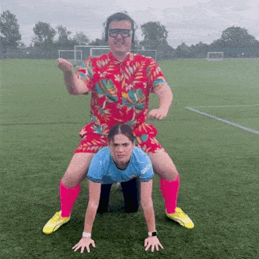 a man in a hawaiian shirt is carrying a woman on his back