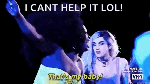 a man and a woman are standing next to each other in a dark room . the woman is wearing a wig .