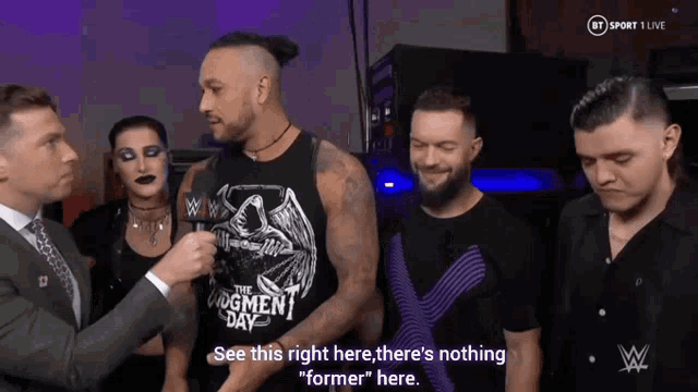 a group of people standing around a man wearing a black tank top that says the judgment day