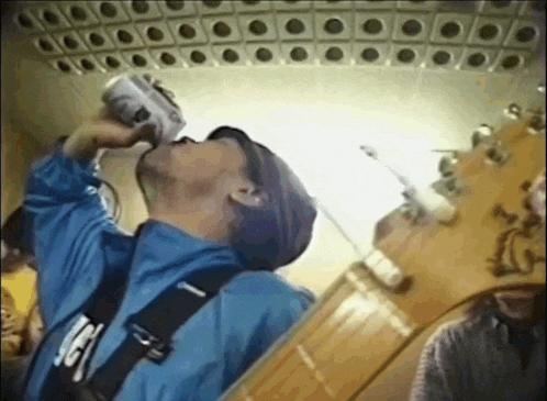 a man drinking from a can with the letter g on his belt
