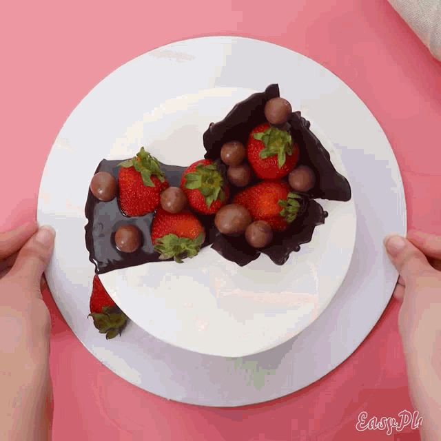 a cake with chocolate covered strawberries and chocolate balls on a plate