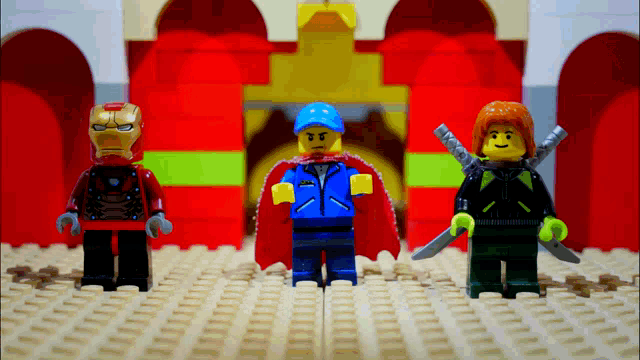 three lego figures are standing in front of a red building