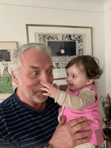 a man is holding a baby in his arms and the baby is touching the man 's face