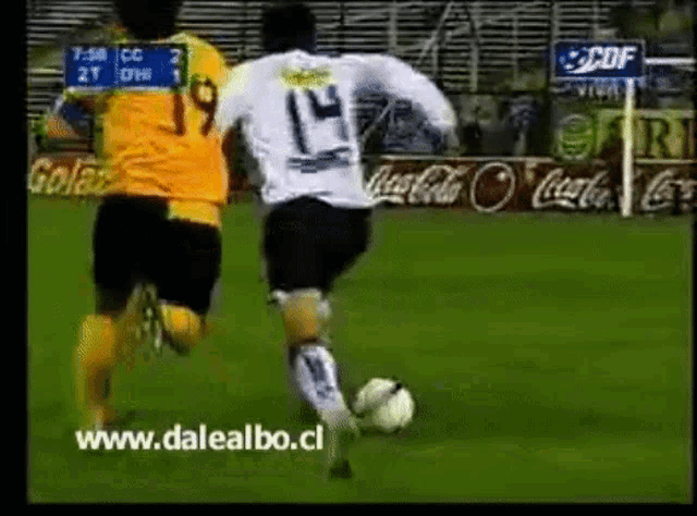 a soccer player wearing the number 14 kicks the ball