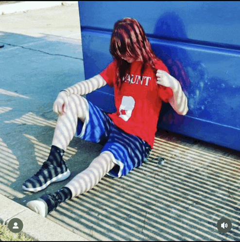 a person wearing a red aunt shirt sits on the ground