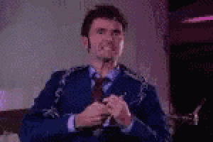 a man in a blue suit and tie is sitting on a couch holding a chain around his neck .