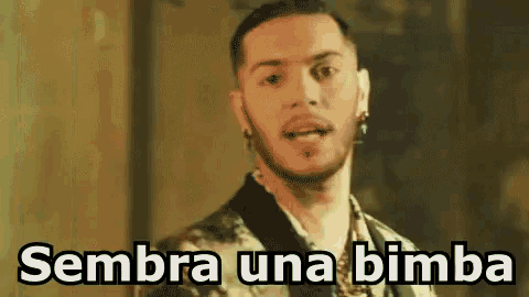 a man in a suit is standing in front of a wall with the words sembra una bimba written on it .